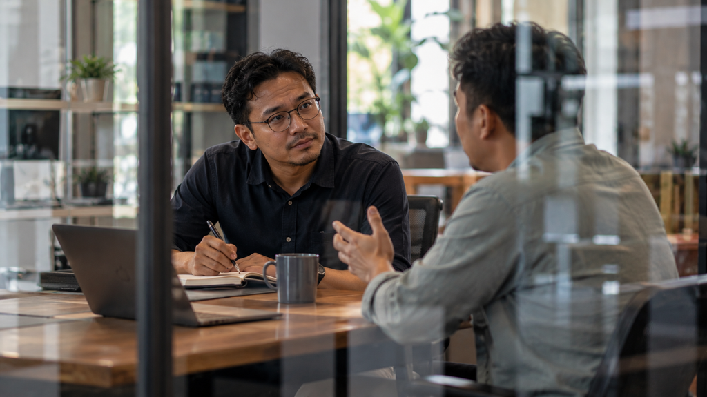 Manajer menulis poin prioritas saat sesi diskusi dengan karyawan.